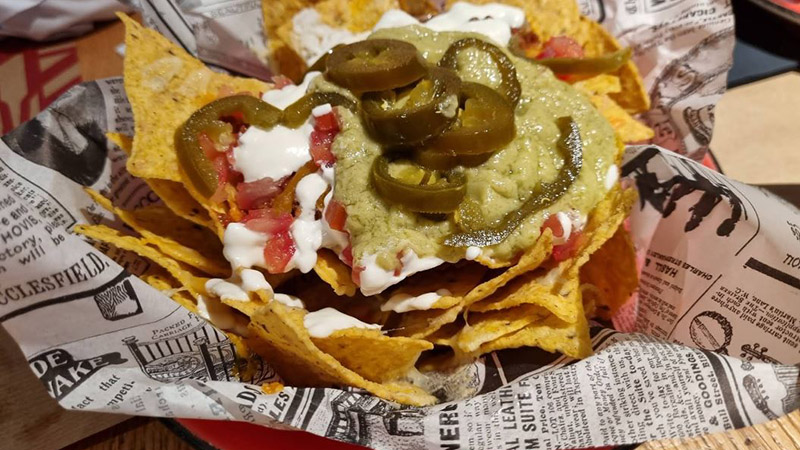 Tex-Mex Nachos, chili con carne, guacamole, melted cheese, sour cream, pico de gallo, and jalapeños - La Fabrica